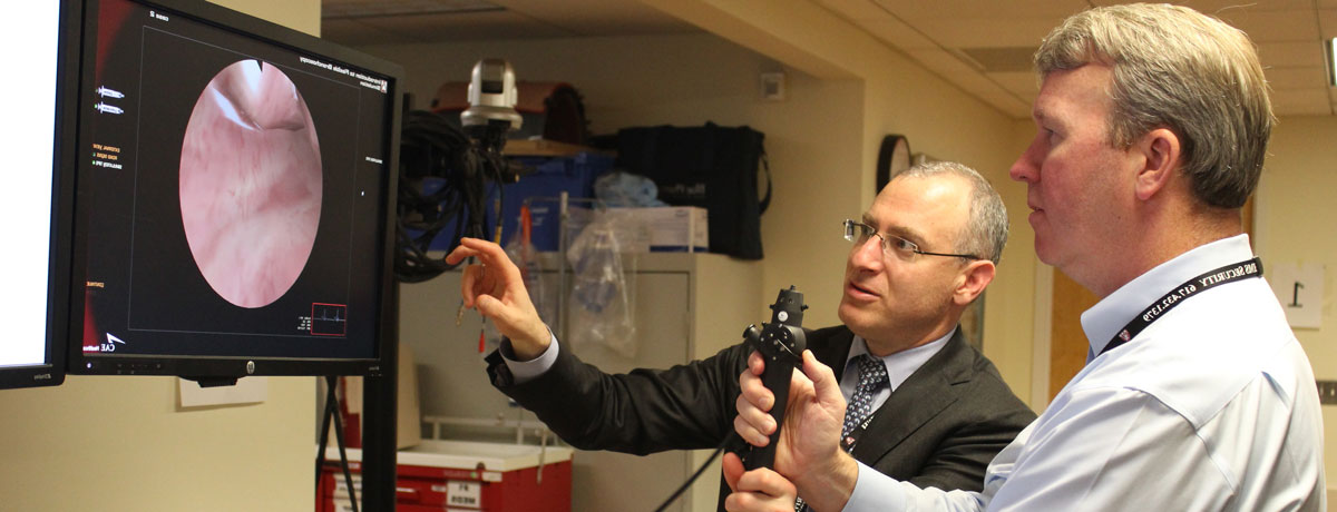Dean David Roberts explains a medical device to an HMS executive education participant.
