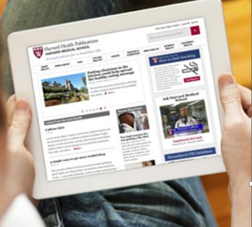 A person using a tablet with the Harvard Health Publishing website on it.